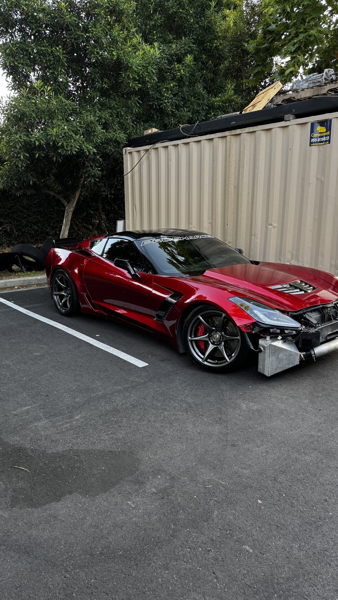Red Corvette outside with front bumper removed and hardware exposed