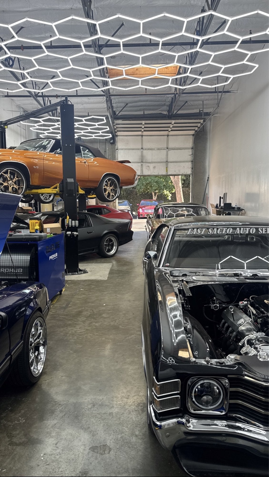 Inside Bay Area Movement Performance with classic cars, lifts, and hexagon lighting